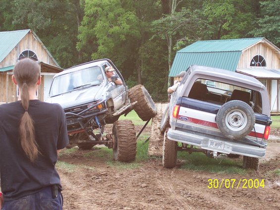 Two off-road trucks in mud, one with a spare tire on the back