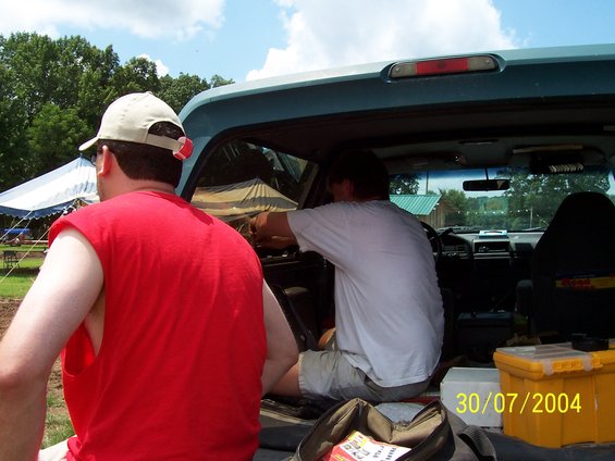 Pickup truck interior with two men, yellow toolbox, and date stamp 30/07/2004