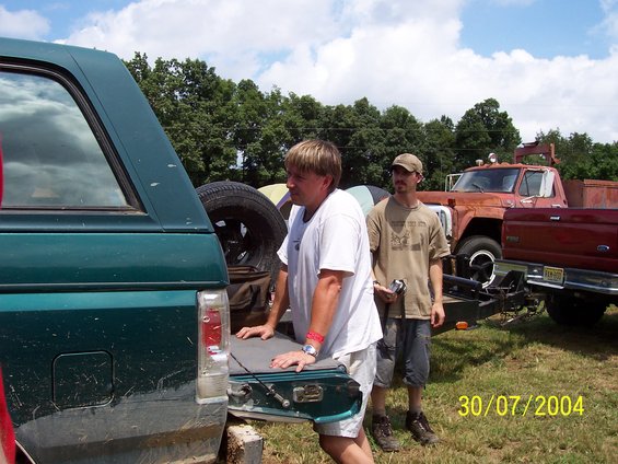 1979 Ford F-150 pickup truck with a trailer, and a green SUV. Two men stand between them