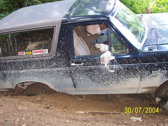 Mud-covered 1979 Ford Bronco stuck in dirt, side view. Date stamp 30/07/2004