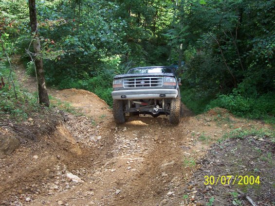 Black Ford F-Series truck with lifted suspension driving on a dirt trail