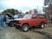 1984 Ford Bronco - A red Ford Bronco with a black top is parked next to a blue Ford truck, with people standing nearby.