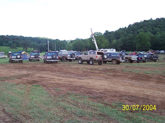Tan Ford Bronco parked in a muddy field with other trucks