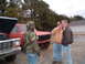 1984 Ford Bronco - Two men converse beside a red truck and a silver truck, which has its hood open.