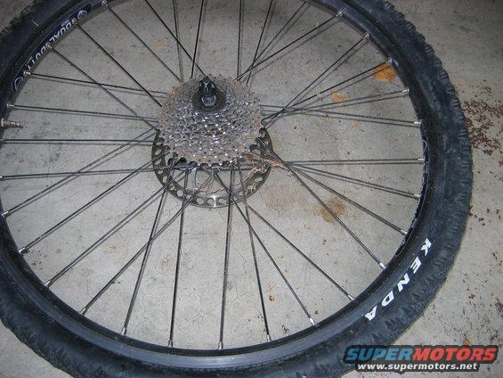 Bicycle wheel with Kenda tire, cassette, and disc brake rotor on concrete floor