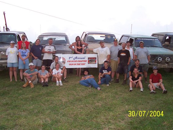 Group of people posing in front of several trucks, with a banner reading '2nd Annual F-150 Dixie Chapter Run In The Sun'. Date stamp reads 30/07/2004