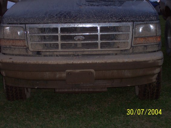 Front view of a muddy truck with a chrome grille and Ford emblem