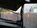 1979 Ford Bronco - The interior of a vehicle shows damage to its roof structure and door seal, with a satellite dish visible outside.