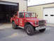 1973 Ford F-250 - A vintage red fire truck is parked outside a building with garage doors.