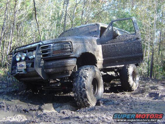 Muddy truck with open door, stuck in a wooded area