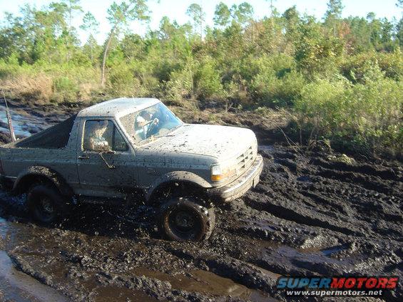 Mud-covered 1992 Ford Bronco stuck in thick mud, front 3/4 view
