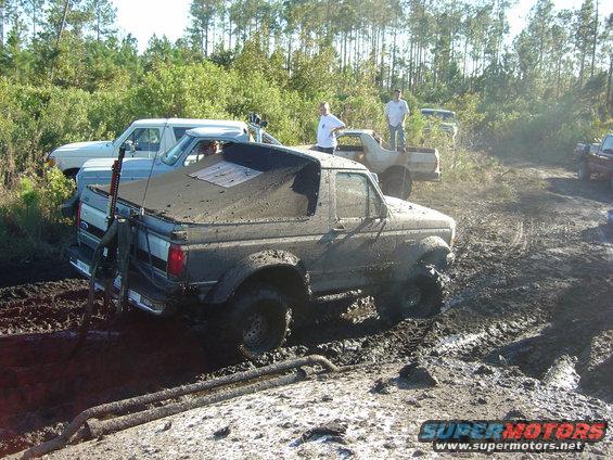 Mud-covered 1993 Ford Bronco stuck in mud with other trucks nearby