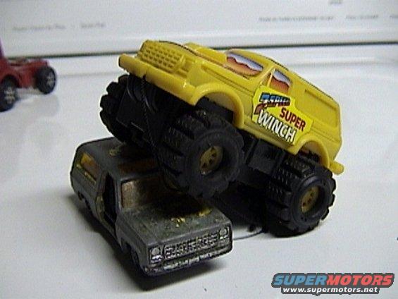 Yellow toy monster truck with 'Super Winch' text on top of a gray toy truck