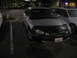2002 Ford Taurus - A silver sedan with a black car bra is parked in a lot at night, with another vehicle visible to its right.