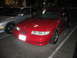 2002 Ford Taurus - A red sedan is parked in a lot next to a silver car.