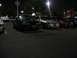 2002 Ford Taurus - Several cars parked in a lot at night, including a 2002 Ford Taurus.
