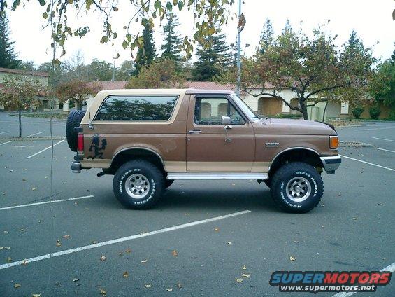 Brown 1990 Ford Bronco, side view, lifted with spare tire on rear