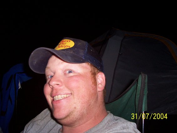 Man in Bass Pro Shops hat smiles, tent in background, date 31/07/2004 visible