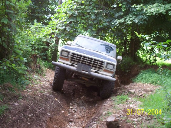 1979 Ford F-150 driving on a dirt trail with trees on both sides