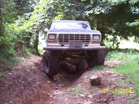 1979 Ford F-150 on a dirt trail, front view, lifted suspension, large tires, custom bumper