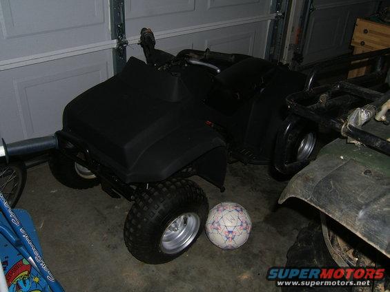 Black ATV with silver wheels and a soccer ball next to it