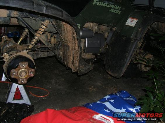 Green Honda Foreman 400 ATV with front wheel removed, supported by a jack