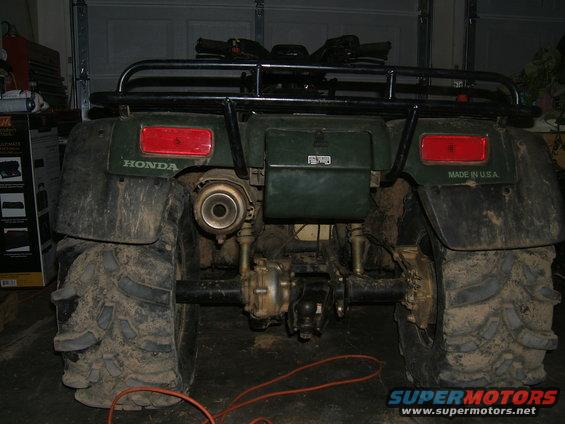 Rear view of a green Honda ATV with large tires and a prominent exhaust pipe