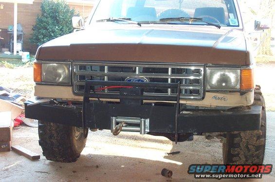 Front view of a brown Ford Bronco with a custom winch bumper and grille guard