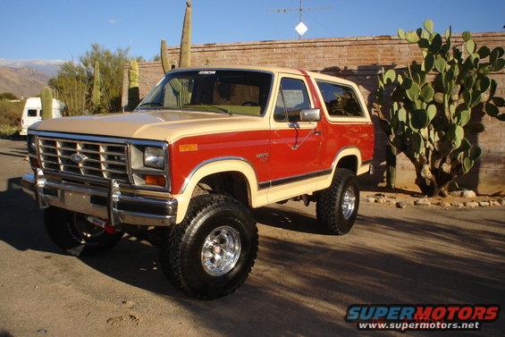 Red and tan Ford Bronco with a lift kit parked outdoors