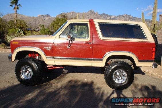 Lifted 1985 Ford Bronco, two-tone red and tan, side view