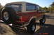 1985 Ford Bronco - This lifted Ford Bronco is parked on a road with desert vegetation in the background.