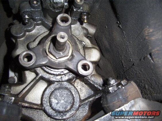 Close-up of greasy engine component with three bolts
