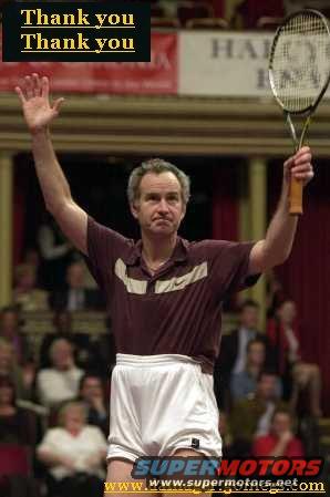 John McEnroe holding a tennis racket with arms raised