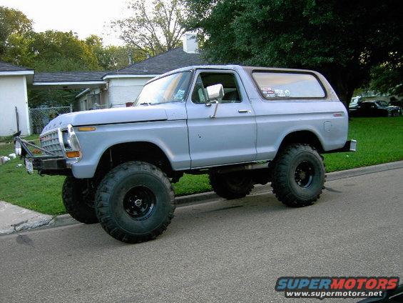 Lifted light blue Bronco with big tires parked on a street