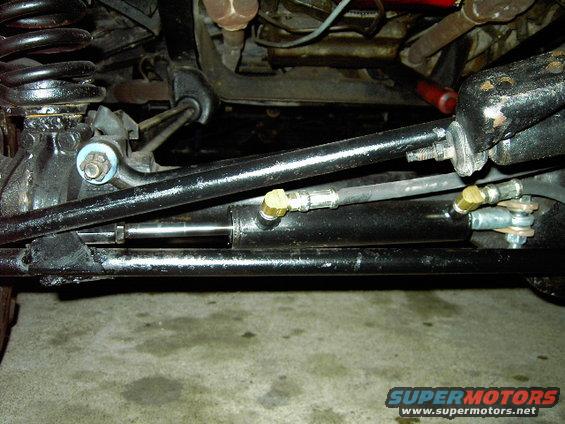 Close-up of black steering linkage and suspension parts, including a shock absorber and tie rod ends
