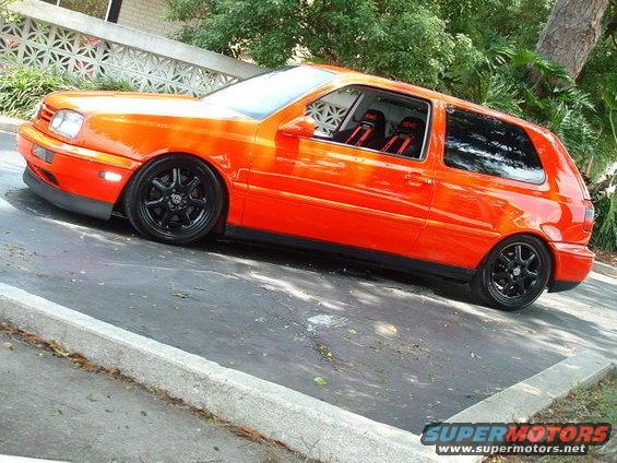 Orange hatchback with black wheels and racing seats