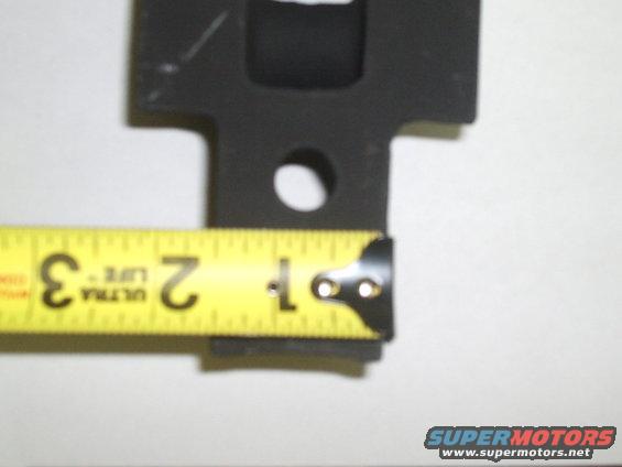 Black metal part measured with a yellow tape measure showing approximately 2 inches