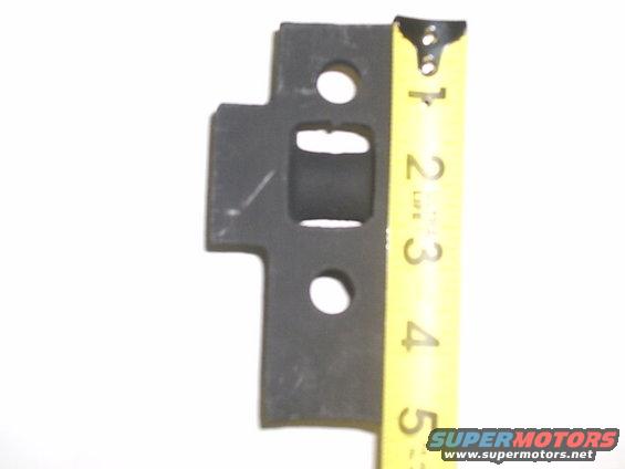 Black metal part with rectangular cutout and two holes, next to a yellow measuring tape showing inches 1-5