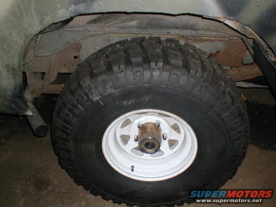 Tire and wheel well of a vehicle, showing rust and damage