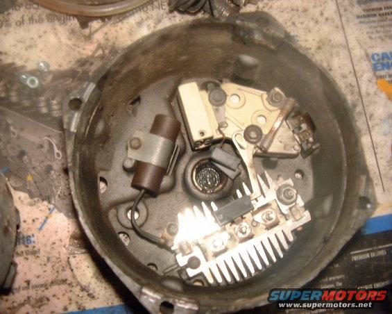 Inside of a disassembled car alternator showing the regulator and rectifier components