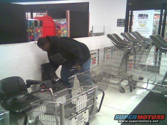 Shopping carts lined up in a store aisle with a person bending over one