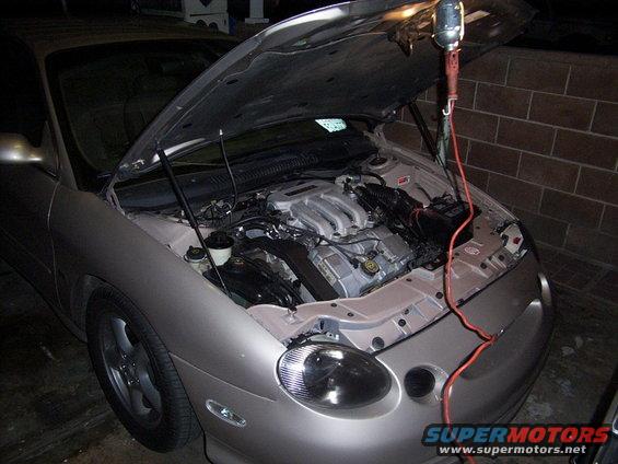 Car with hood open, engine exposed, work light hanging above. Looks like a 1998 Mercury Sable