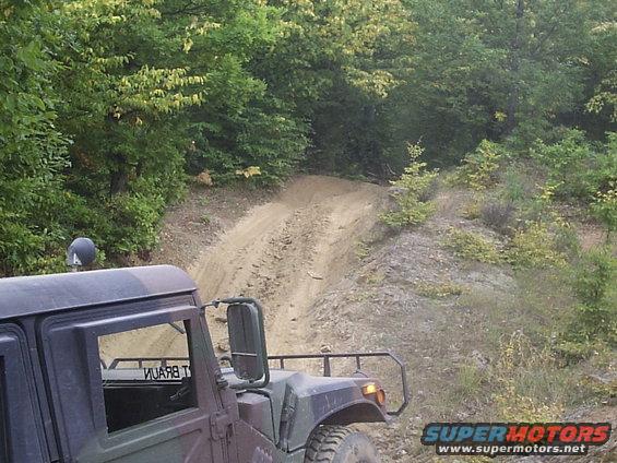 Humvee driving on a dirt road uphill, camouflage paint, visible text on door