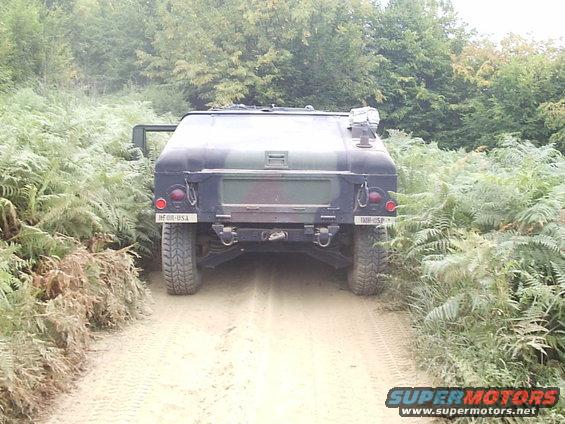 Rear view of a camouflaged military vehicle on a dirt path