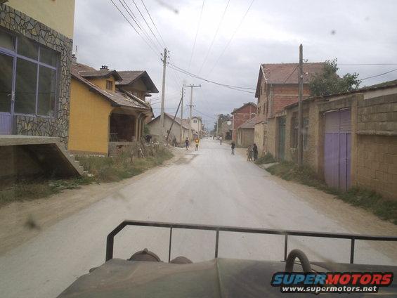 View down a street in a village with houses and people walking