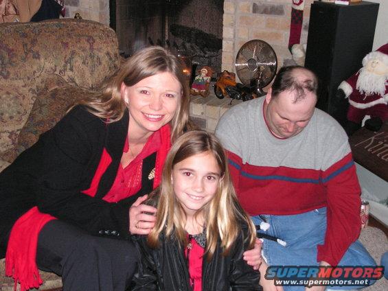 Family posing for a Christmas photo in front of a fireplace