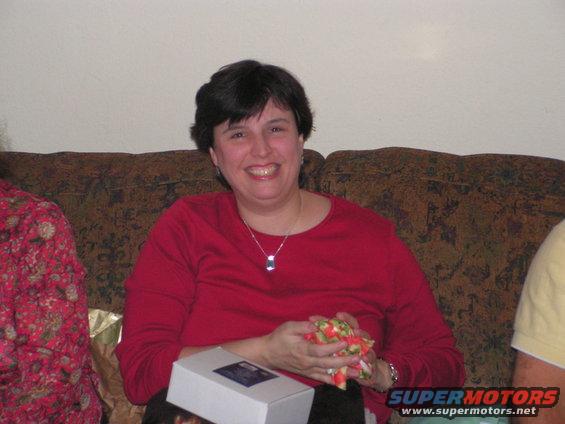 Woman in red shirt sitting on a couch, holding a small gift