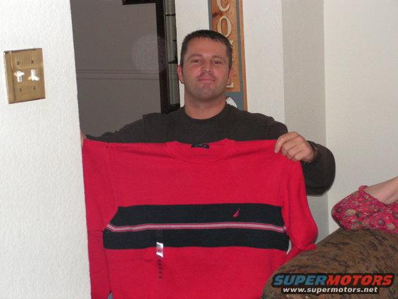 Man holding a red and black striped sweater with a small white logo