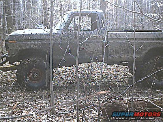 Side view of a muddy 1978 Ford F-250 pickup truck in a wooded area