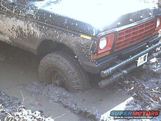 Mud-covered 1979 Ford F-Series truck front end stuck deep in mud